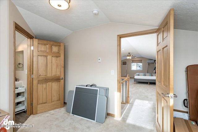 hallway with baseboards, light colored carpet, vaulted ceiling, a textured ceiling, and an upstairs landing