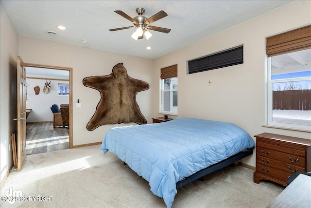 bedroom with light carpet, multiple windows, baseboards, and a textured ceiling