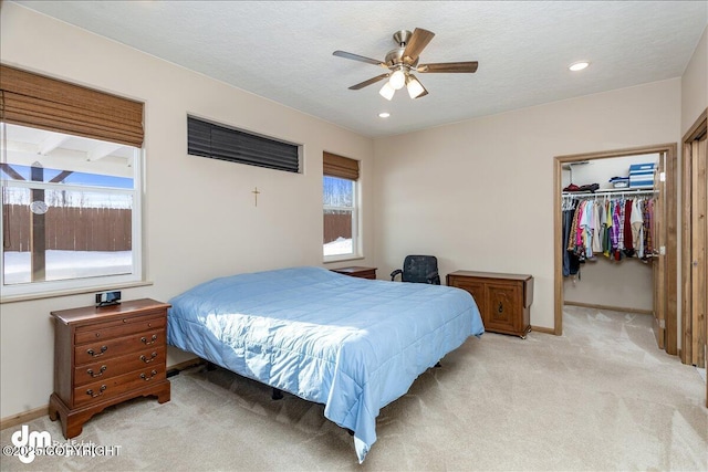 bedroom with a walk in closet, a closet, light colored carpet, and multiple windows