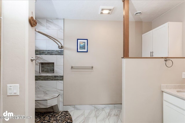 bathroom featuring a walk in shower, a textured ceiling, visible vents, vanity, and marble finish floor