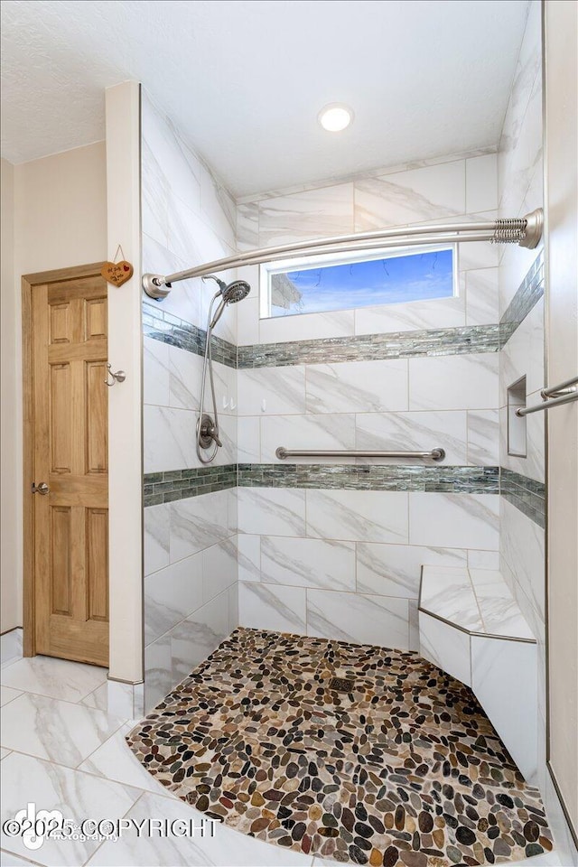 full bathroom with marble finish floor and tiled shower