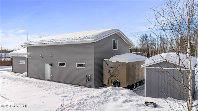 snow covered house featuring an outdoor structure