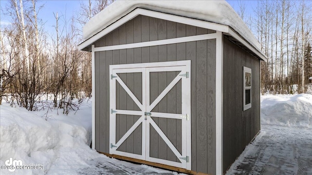 snow covered structure featuring an outbuilding and a storage unit