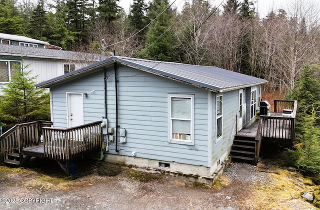 view of home's exterior featuring crawl space, metal roof, and a deck