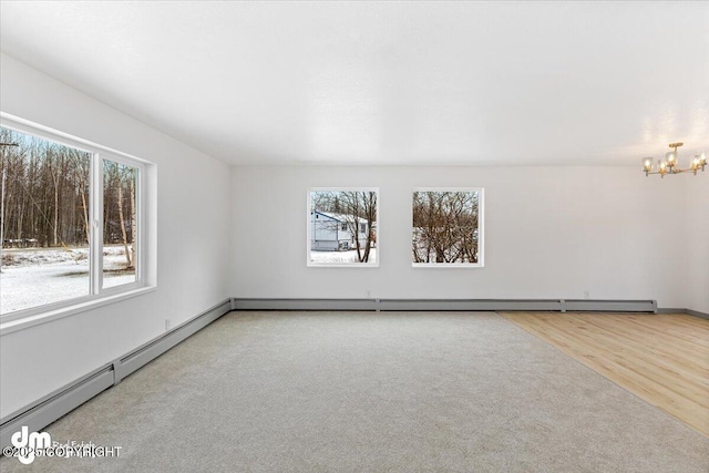 spare room featuring a baseboard heating unit, plenty of natural light, wood finished floors, and an inviting chandelier