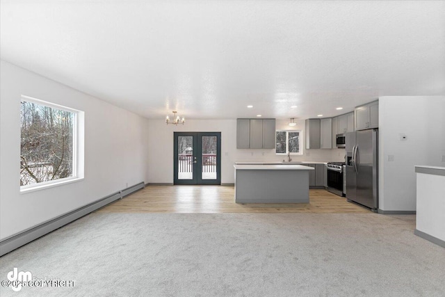 kitchen featuring light carpet, baseboard heating, stainless steel appliances, and gray cabinetry