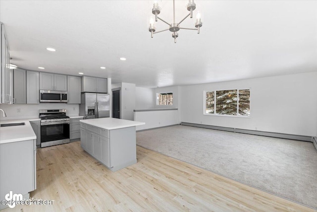 kitchen featuring a center island, light countertops, gray cabinetry, appliances with stainless steel finishes, and a sink