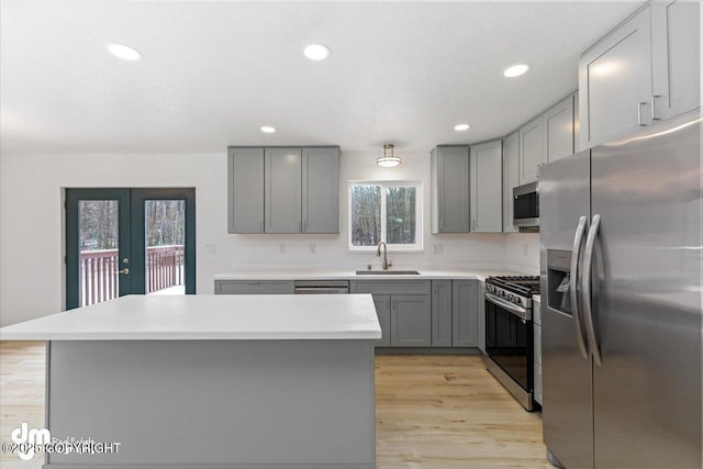 kitchen with french doors, light countertops, gray cabinets, stainless steel appliances, and a sink