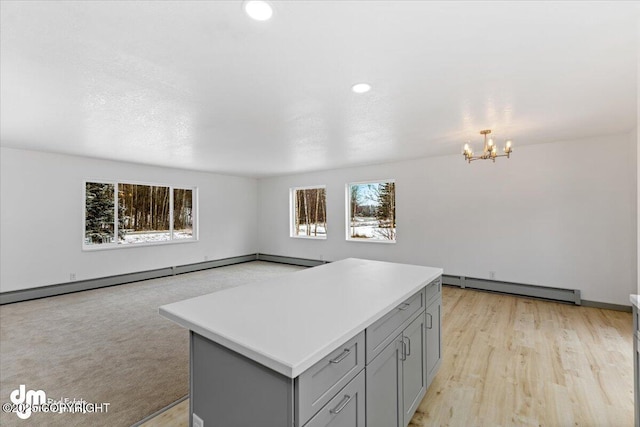 kitchen with a baseboard heating unit, gray cabinets, light countertops, and a kitchen island