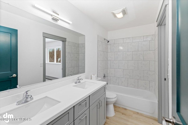 full bath featuring shower / tub combination, a sink, toilet, and wood finished floors