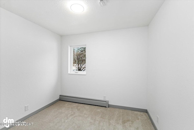 empty room with carpet floors, a baseboard radiator, and baseboards