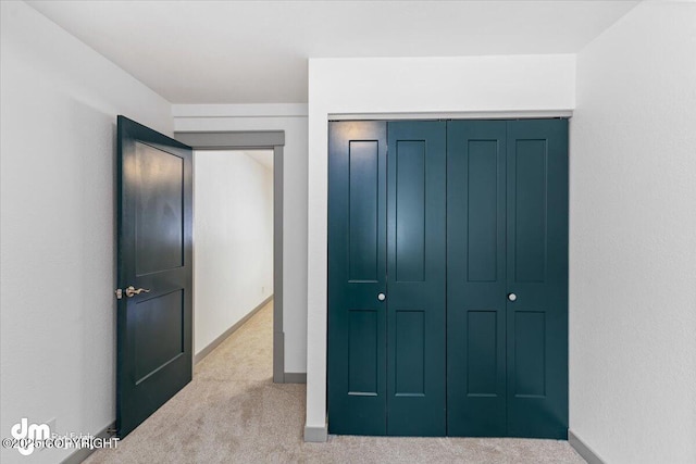 carpeted bedroom featuring baseboards and a closet