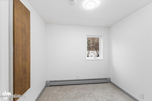 carpeted empty room with a baseboard heating unit, a textured ceiling, and baseboards