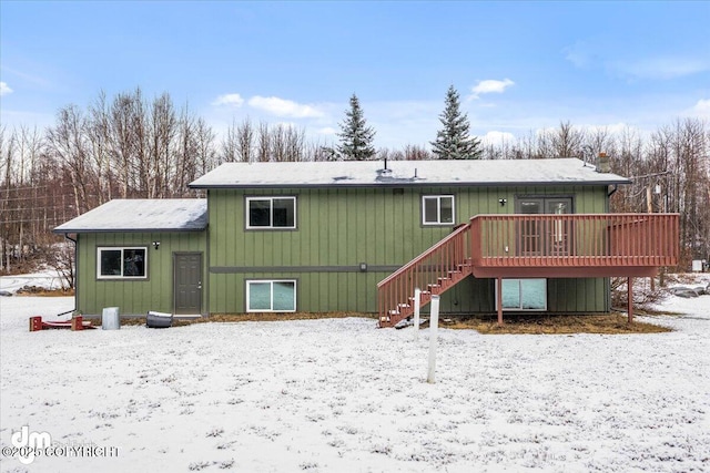 snow covered back of property featuring stairs and a wooden deck