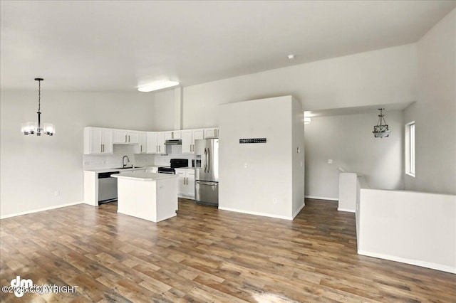 kitchen featuring stainless steel appliances, open floor plan, a sink, a chandelier, and a kitchen island
