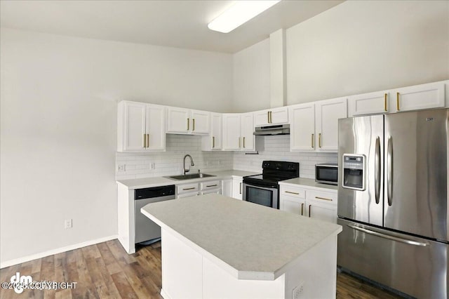 kitchen featuring appliances with stainless steel finishes, a sink, under cabinet range hood, tasteful backsplash, and light countertops