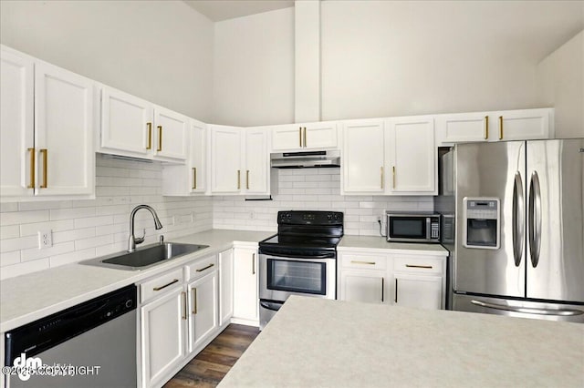 kitchen with appliances with stainless steel finishes, a sink, under cabinet range hood, light countertops, and white cabinets