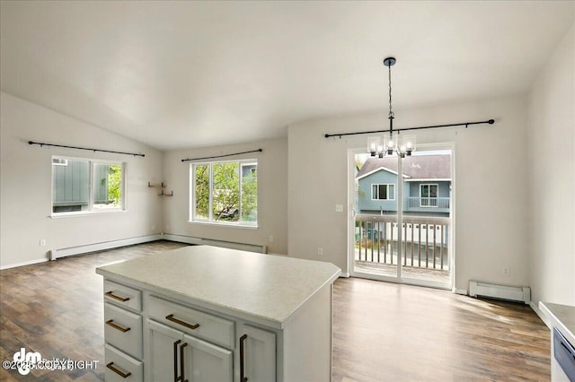 kitchen with a chandelier, wood finished floors, a baseboard heating unit, open floor plan, and light countertops