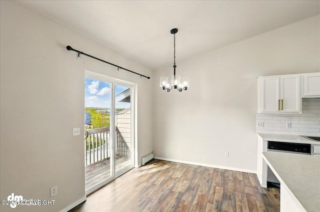 unfurnished dining area with baseboard heating, a chandelier, wood finished floors, and baseboards