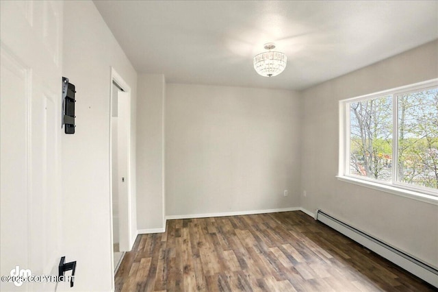 spare room featuring baseboard heating, wood finished floors, and baseboards