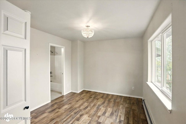 empty room with plenty of natural light, wood finished floors, baseboards, and a chandelier