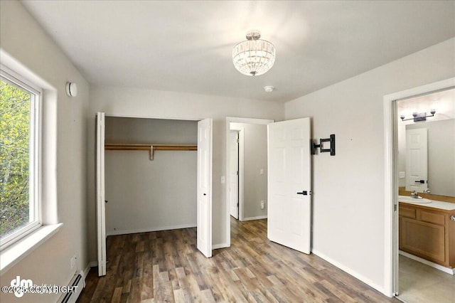 unfurnished bedroom with a sink, a chandelier, a closet, light wood-style flooring, and baseboards