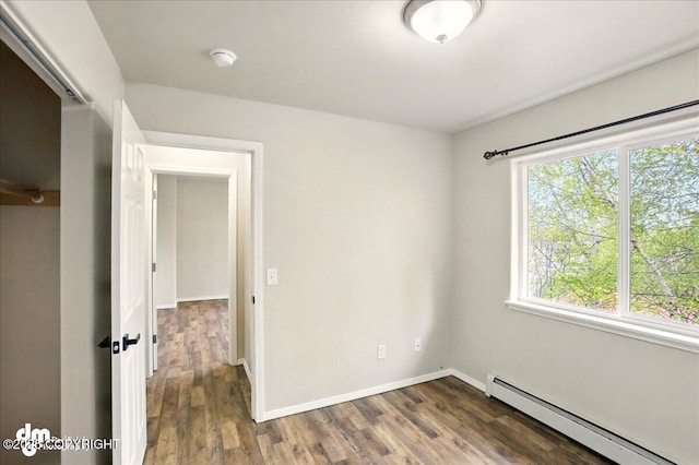 empty room with a baseboard radiator, healthy amount of natural light, and wood finished floors