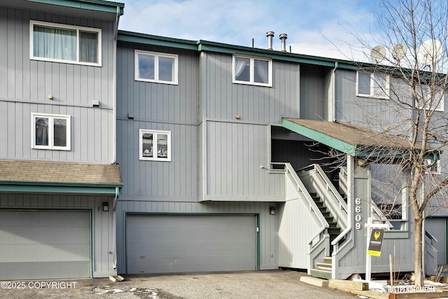 view of front of house with a garage, roof with shingles, and stairs