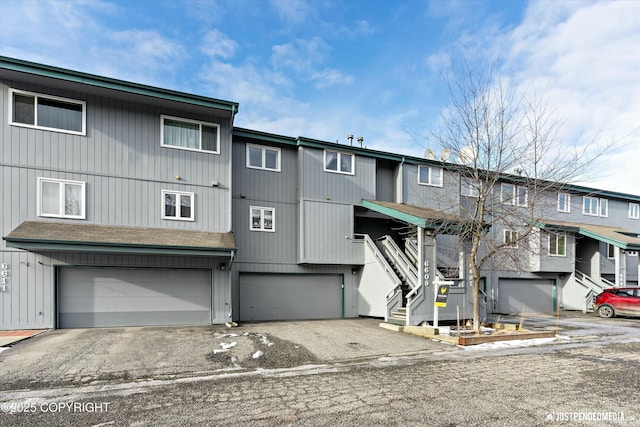 multi unit property featuring driveway, stairway, and an attached garage