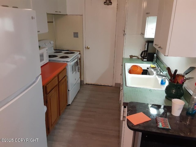 kitchen with light wood-style floors, dark countertops, white appliances, and white cabinetry