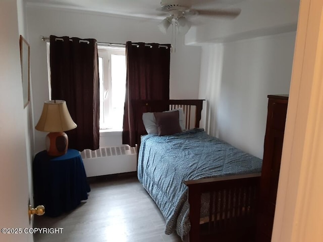 bedroom featuring radiator, light wood-type flooring, and ceiling fan