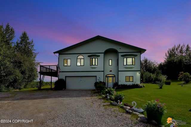 view of front of home featuring gravel driveway, a deck, a garage, and a front lawn