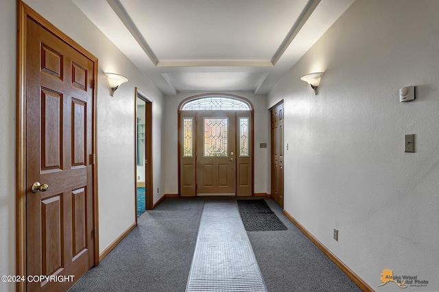 foyer entrance featuring dark colored carpet and baseboards