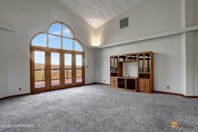 unfurnished living room featuring high vaulted ceiling, carpet floors, visible vents, baseboards, and french doors