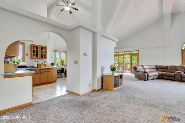 living area featuring arched walkways, a ceiling fan, light carpet, high vaulted ceiling, and baseboards