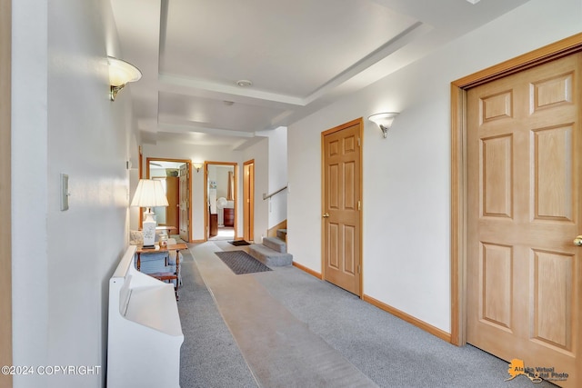 corridor featuring light carpet, baseboards, and stairs