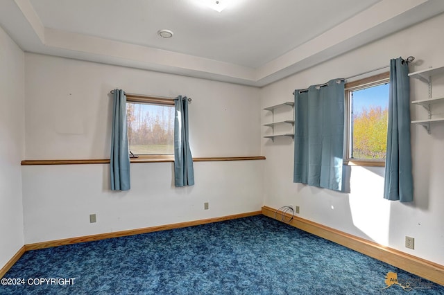 spare room with dark colored carpet and baseboards