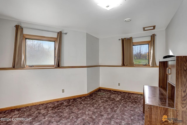 empty room with dark colored carpet and baseboards