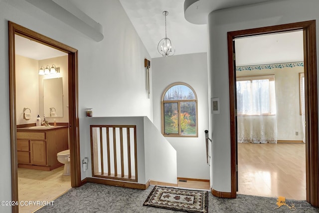 foyer featuring vaulted ceiling, an inviting chandelier, baseboards, and light wood-style floors