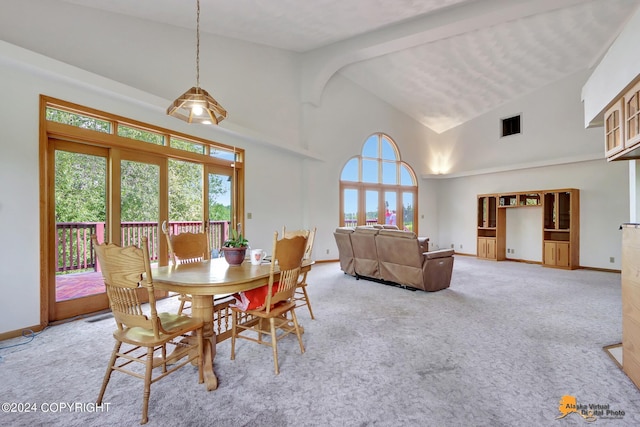 dining area with baseboards, visible vents, high vaulted ceiling, and light colored carpet