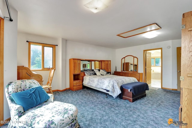 bedroom featuring ensuite bathroom, dark colored carpet, attic access, and baseboards