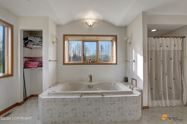 bathroom featuring a garden tub, vaulted ceiling, visible vents, and baseboards