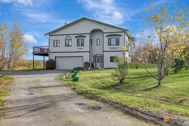 traditional home with a front yard, driveway, a wooden deck, and an attached garage