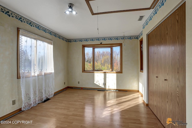 spare room featuring visible vents, light wood-type flooring, attic access, and baseboards