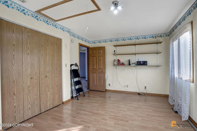 interior space with baseboards, attic access, and light wood-style floors