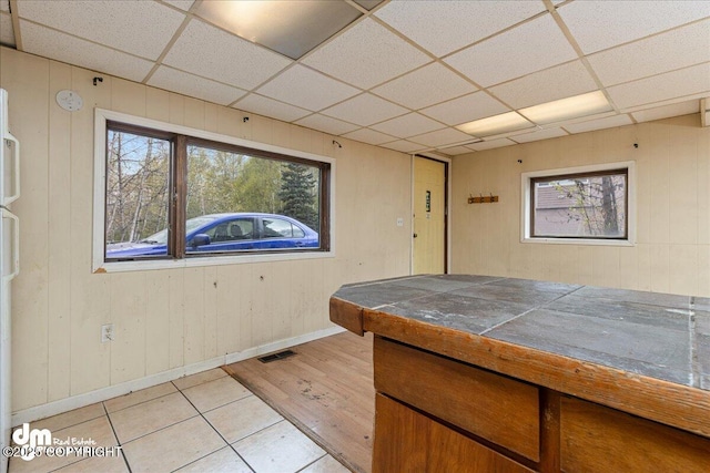 541 E 22nd Ave, Anchorage, AK 99503 - kitchen featuring tile counters, light wood-type flooring, a drop ceiling, baseboards, and wood walls