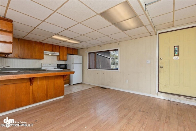 541 E 22nd Ave, Anchorage, AK 99503 - kitchen with white appliances, brown cabinets, light wood-style floors, a paneled ceiling, and under cabinet range hood