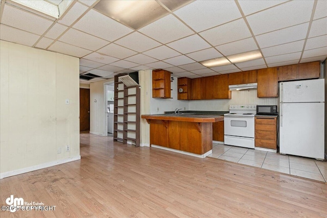 541 E 22nd Ave, Anchorage, AK 99503 - kitchen with white appliances, brown cabinetry, light wood finished floors, under cabinet range hood, and a drop ceiling