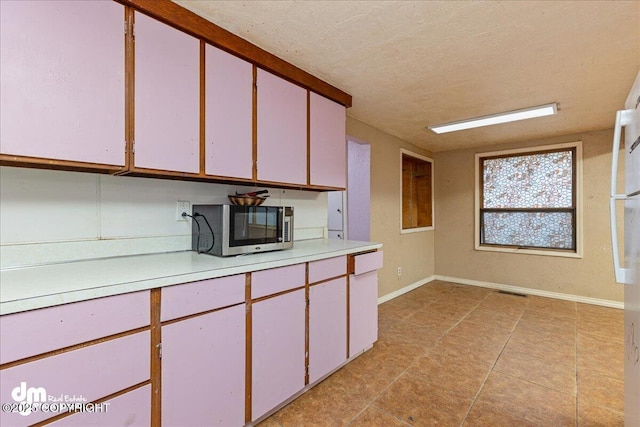 541 E 22nd Ave, Anchorage, AK 99503 - kitchen featuring stainless steel microwave, light countertops, light tile patterned flooring, baseboards, and a textured ceiling