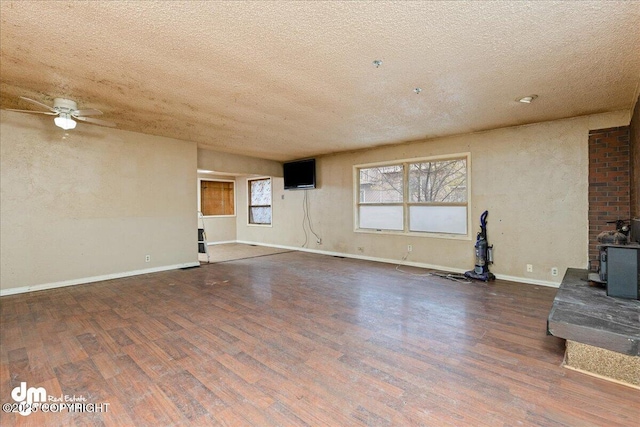 541 E 22nd Ave, Anchorage, AK 99503 - unfurnished living room featuring a wood stove, a textured ceiling, wood finished floors, ceiling fan, and baseboards